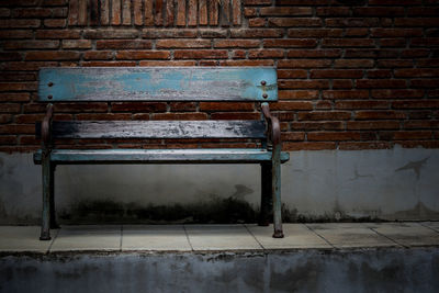 Empty bench against brick wall
