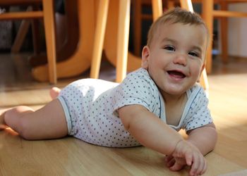 Portrait of cute cheerful baby boy lying on floor at home