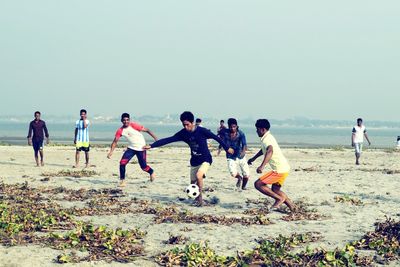 Children playing on beach against sky