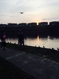 Silhouette man standing on airplane against sky during sunset