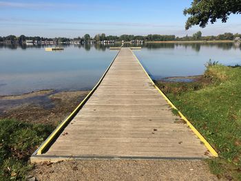 Boardwalk by lake against sky