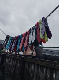 Wet clothespins hanging on clothesline against sky