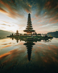 Reflection of building on lake against sky during sunset