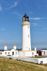 Lighthouse on beach against sky