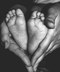 Cropped hands of parent holding baby legs