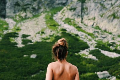 Rear view of shirtless woman against mountain