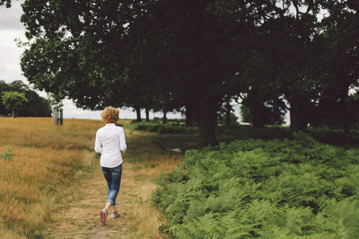 Full length rear view of young woman walking on footpath