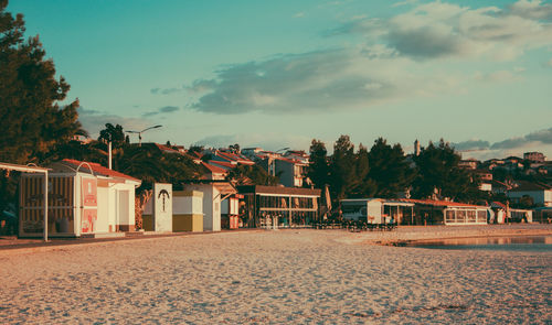 Houses on beach against sky during sunset