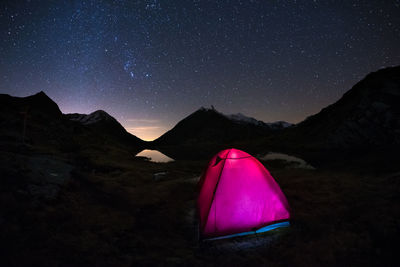 Tent against mountain range at night