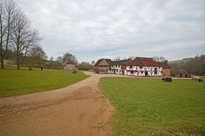 Houses on field by buildings against sky