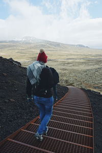 Rear view of woman walking staircase at volcanic mountain