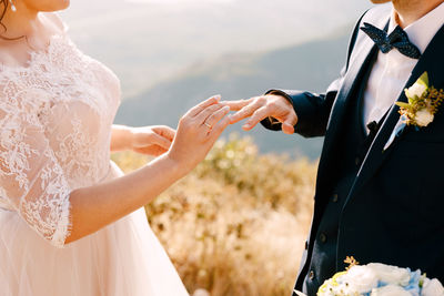 Midsection of couple doing engagement outdoors