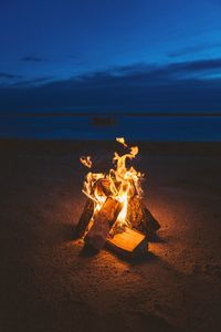 Close-up of bonfire on beach against sky at night