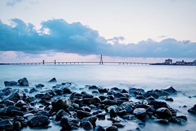 Bridge over sea against sky during sunset