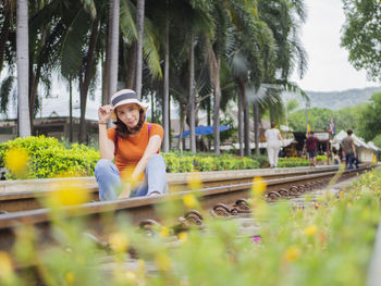 Portrait of woman wearing hat sitting on railroad track