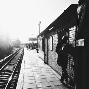 People at railroad station platform against clear sky
