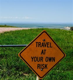 Close-up of information sign on field by sea against sky