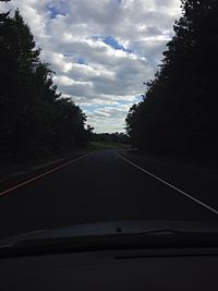 Empty road against cloudy sky