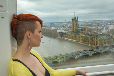 Portrait of young woman on bridge over river in city