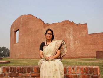 Portrait of woman sitting against built structure