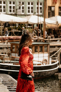 Side view of woman looking away while standing in city