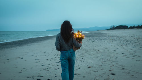 Young girl walks on the beach at blue hour