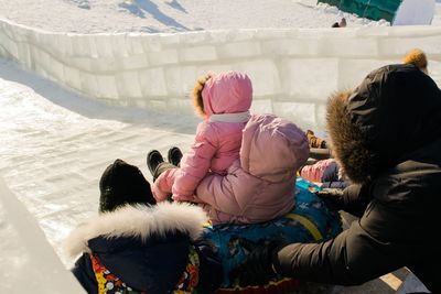 Rear view of people sitting in snow