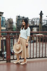 Portrait of smiling young woman standing against railing