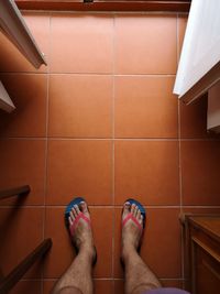 Low section of person standing on tiled floor at home