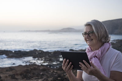 Smiling woman using digital tablet at beach