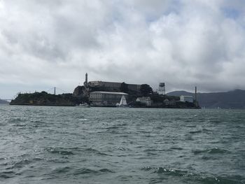 Buildings by sea against sky