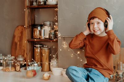 Boy in the kitchen listening to music through wireless headphones. boy listens to music.