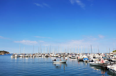 Boats moored at harbor against blue sky