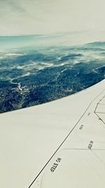 Close-up of airplane wing over sea against sky