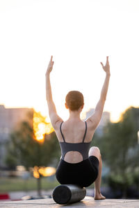 Rear view of woman exercising against clear sky