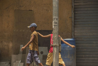 Boys passing by a drum and street light pole