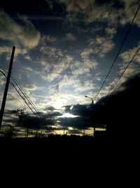 Low angle view of silhouette electricity pylon against sky