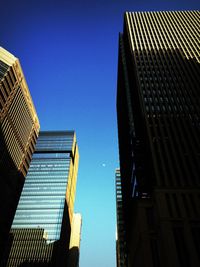 Low angle view of skyscrapers against clear blue sky