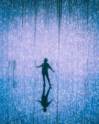 Full length of silhouette man walking against blue water