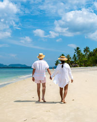 Rear view of woman walking at beach against sky