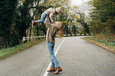 Laughing mother throws up her little cheerful daughter in her arms.