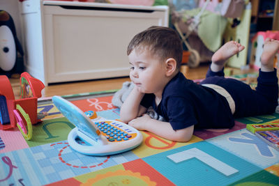 Curious little toddler playing with his toy computer