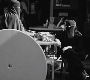 Female friends in hijab sitting at table in cafe