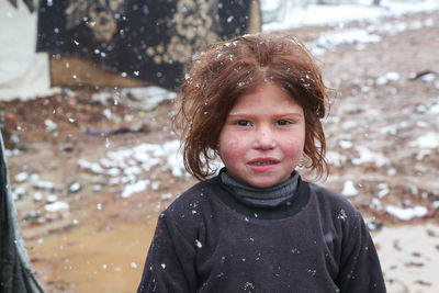 A beautiful refugee girl during a snowfall on a syrian refugee camp near the turkish border