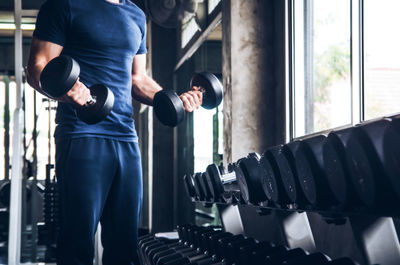 Midsection of man standing doing exercise at gym