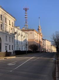 Road by buildings against sky in city