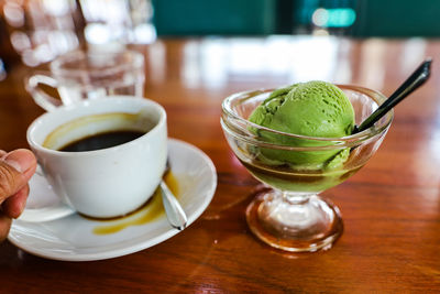 Cup of coffee and green tea ice cream on table