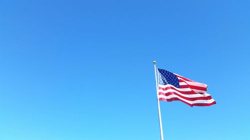 Low angle view of american flag against clear blue sky