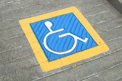 Close-up of wheelchair access sign on road