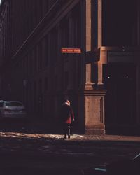 Man walking on street against building at night